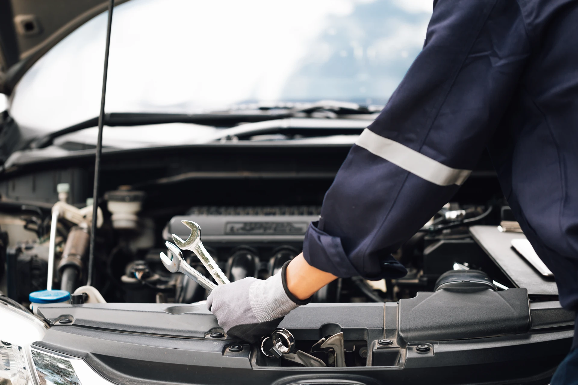 Mécanicien effectuant maintenance automobile, moteur ouvert sous capot véhicule