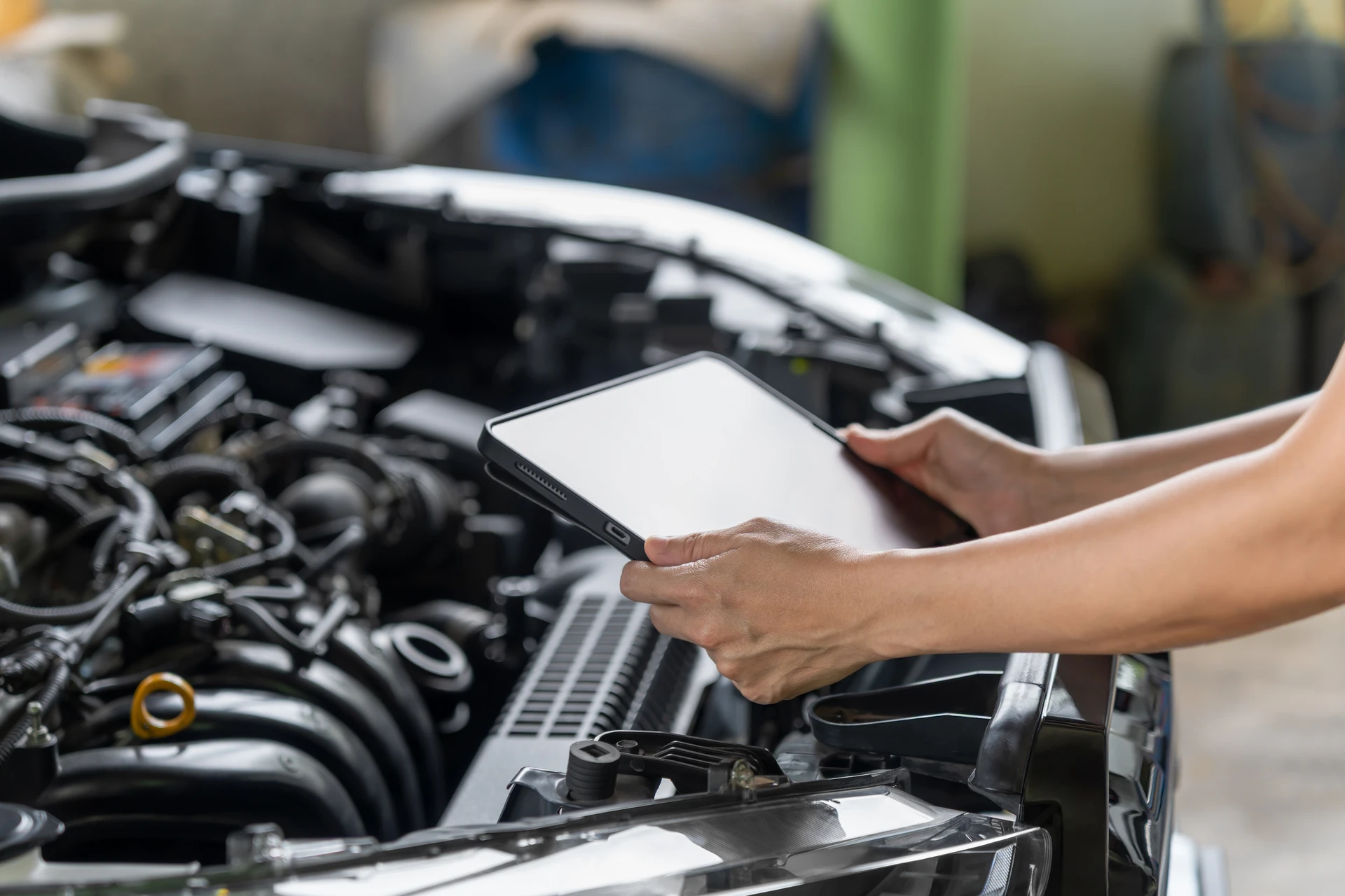 Valise de diagnostic automobile multimarque branchée sur la prise OBD sous le tableau de bord d'un véhicule en atelier mécanique, écran tactile affichant des codes d'anomalie moteur, garage automobile professionnel.